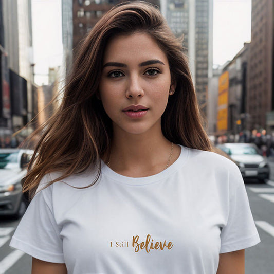 In New York City a young brunette woman wearing a white 100% organic cotton t-shirt that features the positive message, "I Still Believe."