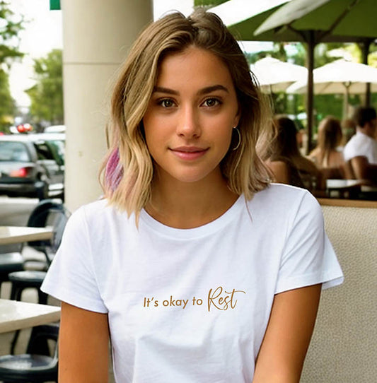 Young blonde woman wearing a white 100% organic cotton t-shirt that features the positive quote, "It's okay to REST."